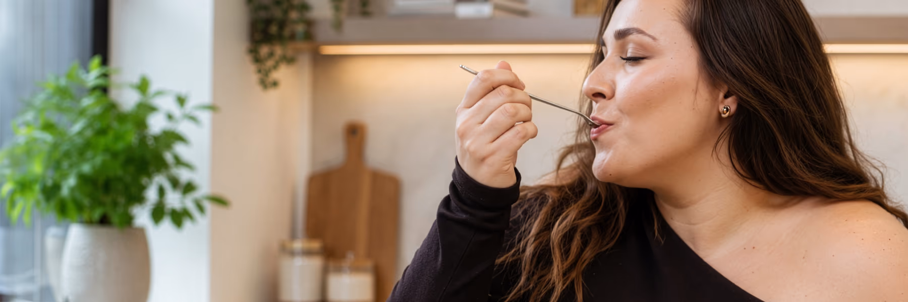 woman enjoys a spoonful of dessert in kitchen setting